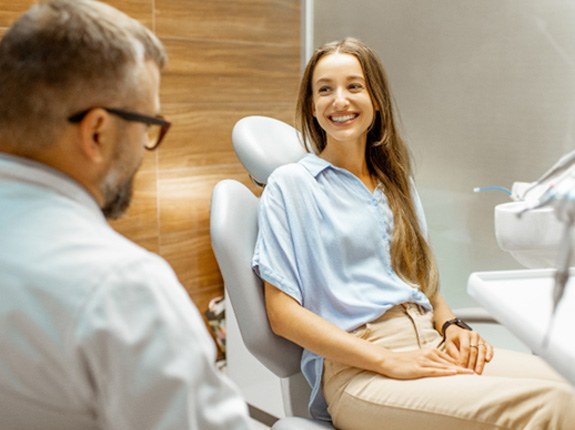 Woman smiling at dentist while sitting in treatment chair