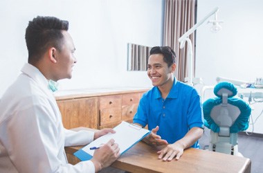 Dentist and patient smiling while reviewing the cost of Invisalign